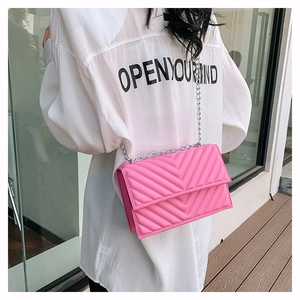 Vue de dos d'un mannequin portant un sac matelassé rose avec motif en V et chaîne argentée