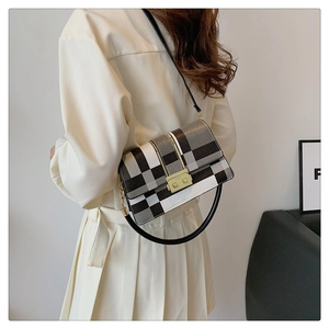 Detail of checkered crossbody bag with golden buckle and sleek black shoulder strap