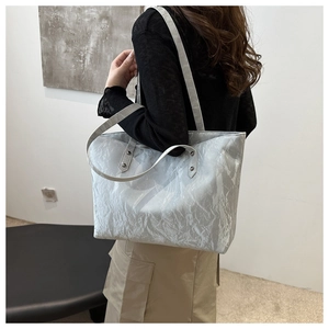 Détail du sac fourre-tout argenté plissé montrant la texture et les rivets métalliques