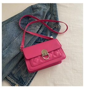 Detail of rose red quilted shoulder bag with silver turn-lock on denim jacket