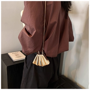 Elegant gold shell evening bag with radial pleats shown on model with chain strap