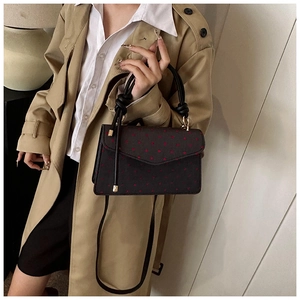 Close-up of black polka dot handbag with knot handle and elegant shoulder strap