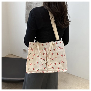 Detail of white canvas tote bag with red cherry prints and two functional front pockets
