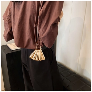 Detailed view of the gold seashell metal chain bag worn on model back for size reference