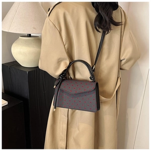 Polka dot crossbody bag styled with a trench coat for a trendy street fashion look
