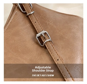 Détail macro d'une bandoulière en cuir marron avec boucle en métal argenté