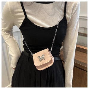 Detail of pink mini crossbody bag with silver butterfly charm and chain strap on model