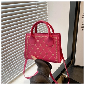 Detail of rose pink quilted crossbody bag featuring gold heart embroidery and wavy stitching