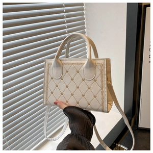 Detail of quilted stitching pattern and small golden heart accents on a mini handbag