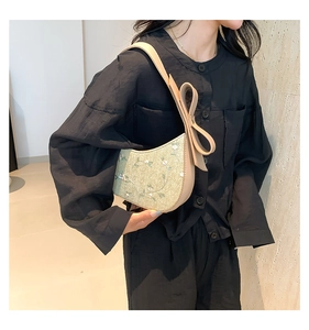 Close-up of floral lace embroidery and a large decorative bow on this chic underarm bag