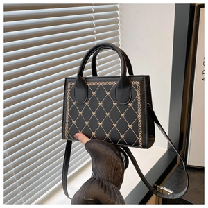 Detail of black quilted leather handbag with gold heart embroidery and adjustable strap