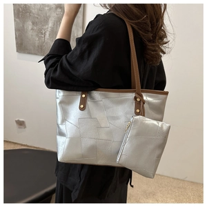 Dettaglio della borsa tote geometrica argento con manici marroni e trama in PU