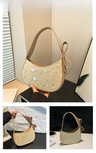 Detail of khaki straw half-moon bag featuring floral embroidery and leather bow accents
