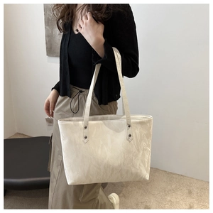 Détail du sac cabas crème avec texture plissée et rivets argentés sur la bandoulière