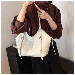 Détail du sac cabas en cuir blanc cassé avec boucles métalliques argentées sur la bandoulière