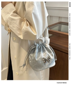 Détail du sac seau argenté avec pendentif papillon et bandoulière en chaîne fine