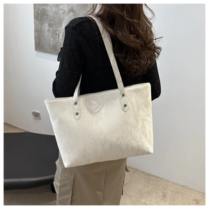 Détail du sac cabas crème avec texture froissée et rivets métalliques de renforcement