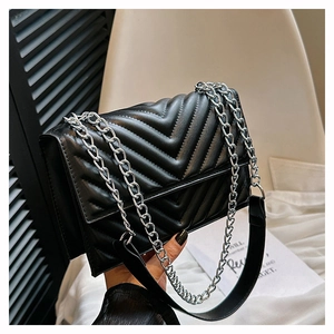 Détail du sac à bandoulière matelassé noir avec chaîne argentée et poignée en cuir