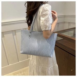 Détail du sac cabas bleu clair avec texture plissée porté à l'épaule pour le style