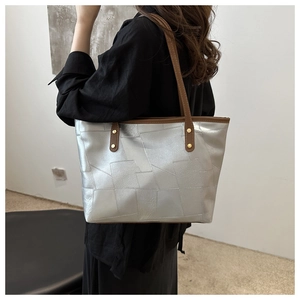 Borsa tote geometrica argento con manici marroni indossata da una modella elegante