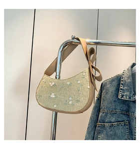 Detailed embroidery of white lace flowers on a light green crescent-shaped shoulder bag