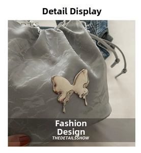 Détail d'un sac seau argenté avec boucle papillon en métal liquide et cordon serrage