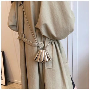 Detail of silver shell-shaped mini crossbody bag with metallic ridges and chain strap