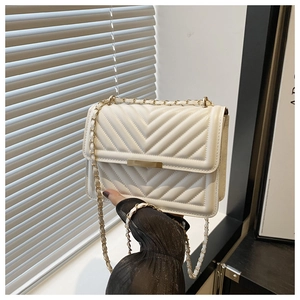 Close-up of white quilted crossbody bag with V-shaped stitching and gold chain strap