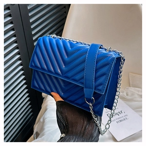 Détail d'un sac bandoulière en cuir matelassé bleu marine avec chaîne argentée à la main