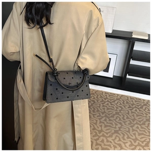 Detail of grey polka dot crossbody bag with a unique knotted handle and shoulder strap