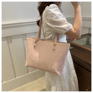 Détail du sac cabas rose clair avec texture froissée et rivets métalliques sur la bandoulière