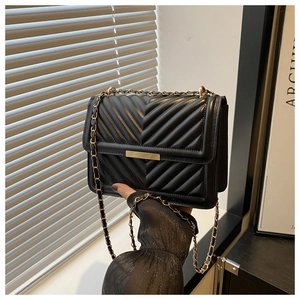 Close-up of black V-quilted faux leather bag with gold metal buckle and chain strap