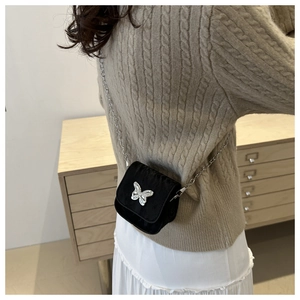 Mini black crossbody saddle bag with silver butterfly and delicate chain strap on model