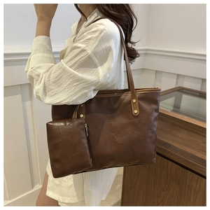 Dettaglio della borsa tote in pelle marrone scuro con cuciture geometriche e borchie