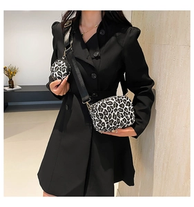 Detail of leopard print crossbody bag with wide black strap and round coin purse on shoulder