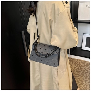 Detailed back view of a grey polka dot handbag with black bow and elegant shoulder strap