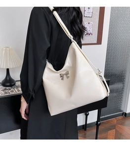 Elegante borsa a tracolla beige con fiocco in metallo argento in un ambiente moderno