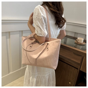 Détail du sac cabas rose minimaliste avec texture fine et rivets sur les bandoulières