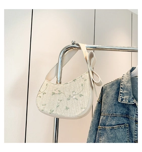 Detail of floral embroidery and bow strap on cream lace underarm bag for summer