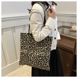 Detail of trendy leopard print tote bag with black leather straps on a model
