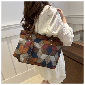 Dettaglio della borsa tote patchwork geometrico con texture coccodrillo e litchi su modella
