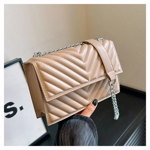 Détail du sac beige matelassé avec coutures en chevron et bandoulière en chaîne argent