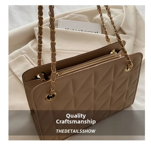 Close-up of beige quilted crossbody bag with gold chain strap and metal zipper detail