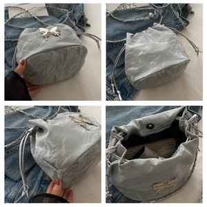 Détails du sac seau argenté avec papillon métallique et bandoulière chaîne élégante