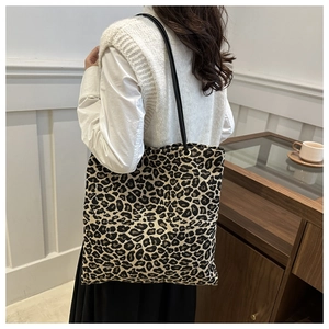 Close-up of leopard print tote bag with gold metal eyelets and black shoulder straps