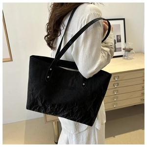 Détail d'un grand sac cabas noir avec texture froissée et rivets argentés discrets