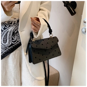 Detailed side view of polka dot square bag with leather handle on white blazer