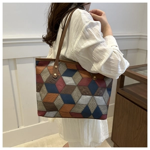 Vista laterale di una grande borsa tote geometrica patchwork con blocchi 3D e pelle