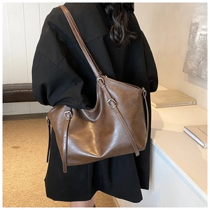 Gros plan sur un grand sac cabas vintage marron avec bandoulière porté par un mannequin