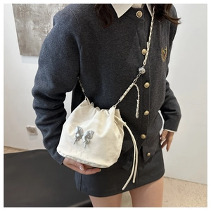 Détail d'un sac seau en satin blanc avec papillon en métal argenté et bandoulière